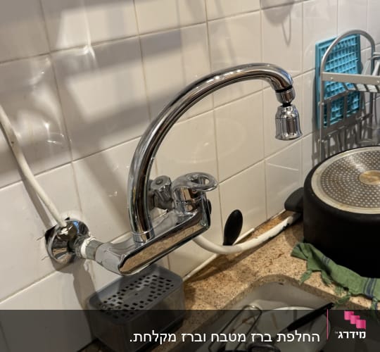 ברז מטבח עם צינור מים לבן על קיר אריחים